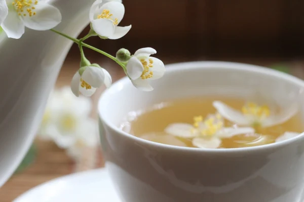 Tách trà với hoa trắng trên mặt trà.